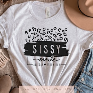 May include: A white t-shirt with a black and white graphic design. The graphic features a leopard print pattern, the words "Sissy Mode", and the text "All Day Every Day".