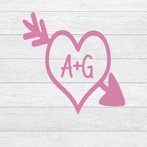 May include: Pink heart with an arrow through it, with the initials A+G inside the heart.