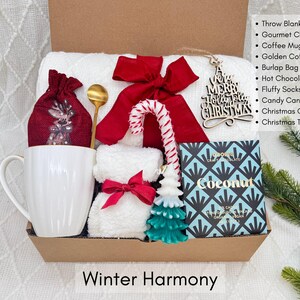 Puede incluir: Una caja de regalo con art&iacute;culos de invierno. Incluye una taza blanca, una bolsa de yute roja, una cuchara dorada, un lazo rojo, un bast&oacute;n de caramelo, un adorno de &aacute;rbol de Navidad, una vela y una caja de chocolate. El texto "Winter Harmony" est&aacute; abajo.