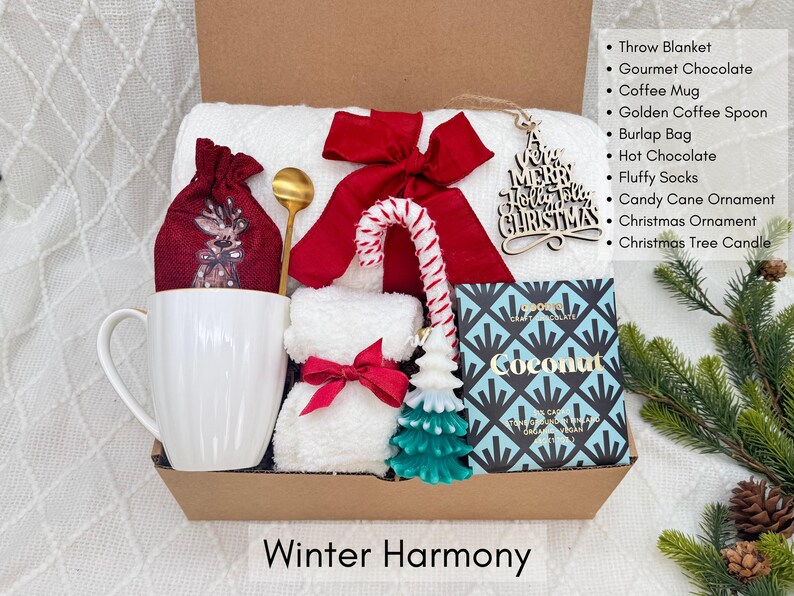 Puede incluir: Una caja de regalo con art&iacute;culos de invierno. Incluye una taza blanca, una bolsa de yute roja, una cuchara dorada, un lazo rojo, un bast&oacute;n de caramelo, un adorno de &aacute;rbol de Navidad, una vela y una caja de chocolate. El texto "Winter Harmony" est&aacute; abajo.