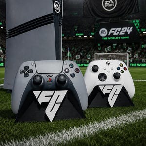 Pode incluir: Uma consola PlayStation 5 cinzenta e um comando cinzento a condizer, juntamente com um comando Xbox branco, todos com a marca EA Sports FC. Os artigos são exibidos num campo de futebol com um grande cartaz EA Sports FC 24 ao fundo.