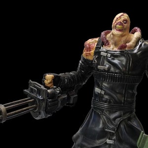 May include: A black and green action figure of a zombie-like creature holding a large machine gun and a rocket launcher. The figure has a grotesque, fleshy appearance with a large, open mouth and exposed teeth. The figure is wearing a black leather jacket and pants.