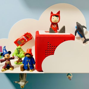 May include: A white cloud-shaped shelf with various toys, including a red toy car, a green tree, a red and white toy speaker, a red toy character, a blue toy character, a blue whale, a blue and white toy character, and a white and blue toy character.