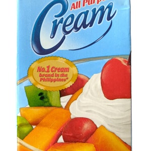 Puede incluir: Una caja azul y blanca de Nestle All Purpose Cream. La caja presenta una sugerencia de servicio de ensalada de frutas cubierta con crema batida. El texto "No. 1 Cream brand in the Philippines" est&aacute; en un sello dorado. La caja es de 250 ml y es crema reconstituida procesada UHT.