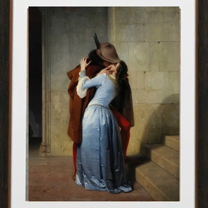 May include: Framed print of a classic painting depicting a romantic embrace. A man in a brown coat and hat kisses a woman in a light blue dress. The artwork is set against a stone wall with stairs.