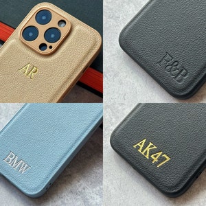 May include: Four different phone cases with personalized initials. The cases are made of leather and come in a variety of colors, including black, blue, and gold.