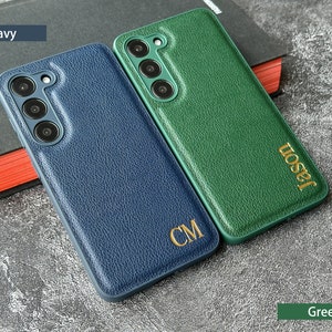 May include: Two personalized phone cases, one navy blue with the initials "CM" and one green with the name "Jason".
