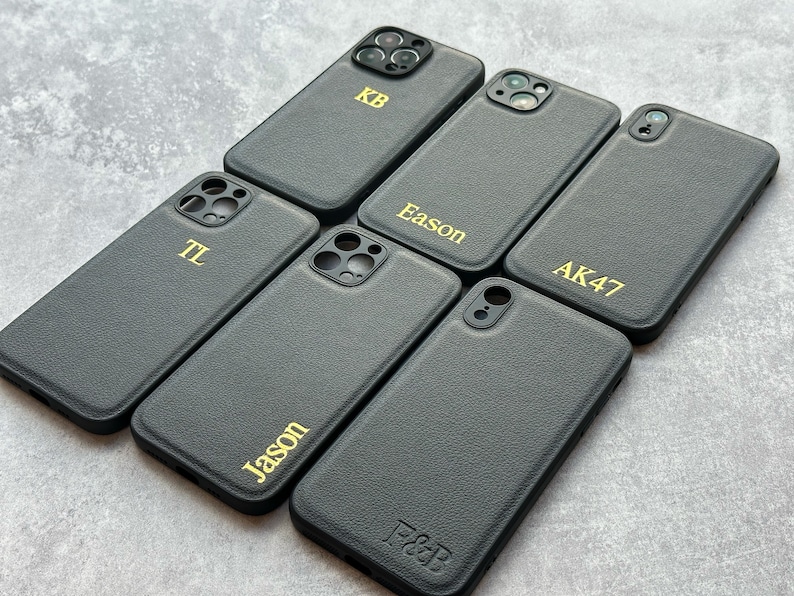 May include: Six black leather phone cases with gold lettering. The cases have different names on them, including "KB", "Eason", "AK47", "TL", "Jason", and "F&B".