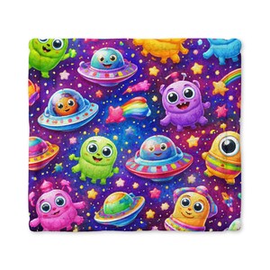 May include: A colorful blanket featuring a repeating pattern of cartoon aliens, UFOs, stars, and rainbows against a dark purple space background. The aliens are various colors, including green, purple, and yellow, with large eyes and friendly expressions.