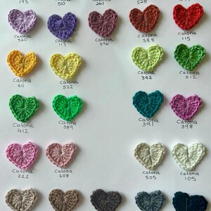 May include: A collection of crocheted hearts in various colors, each labeled with the corresponding Catona yarn number.