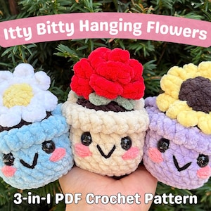 Peut inclure: Trois ornements de pots de fleurs crochetés en bleu, crème et violet, chacun surmonté d'une fleur différente : une marguerite, une rose et un tournesol. Les pots ont des visages souriants. Le texte indique "Itty Bitty Hanging Flowers" et "3-en-1 PDF Crochet Pattern."