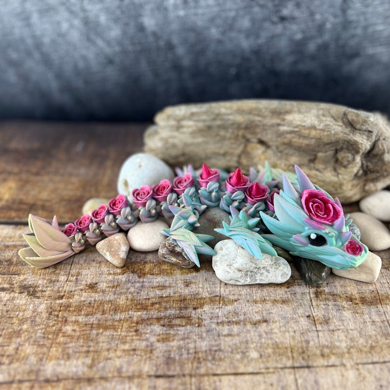 May include: A small, green, and pink dragon figurine with pink rose accents. The dragon is made of polymer clay and has a whimsical, fairytale-like appearance.