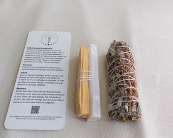 May include: A collection of spiritual items including a sage smudge stick, palo santo, and selenite crystal, with a card detailing their uses. The sage bundle is wrapped with white string. The palo santo and selenite are bundled together.