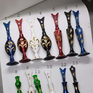 Puede incluir: Trece jarrones decorativos de metal con detalles dorados y varios colores, incluyendo azul, rojo, blanco, negro y verde. Los jarrones están numerados del 1 al 13.