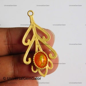 Op de afbeelding: Gouden hanger met een delicaat, versierd bladontwerp met een helder oranje opaal edelsteen in het midden.
