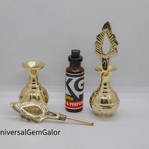 May include: Two gold metal decorative perfume bottles with ornate tops and a small brown glass bottle with a black label that says "KG Gifts & Perfumes".