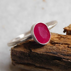 May include: A silver ring with a bright pink oval gemstone.