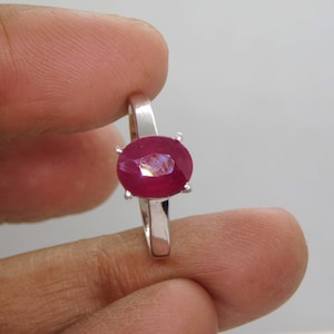 Peut inclure: Une bague en argent avec une grande pierre précieuse de rubis de forme ovale. Le rubis est de couleur rouge foncé et a un léger éclat.