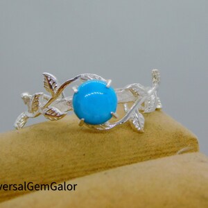 Op de afbeelding: Een zilveren ring met een turquoise edelsteen in een bladmotief.