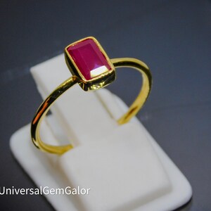 May include: A gold ring with a rectangular red ruby gemstone.
