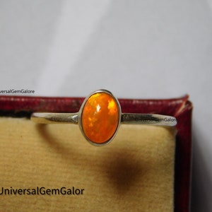 May include: A silver ring featuring an oval orange opal gemstone.