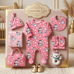 以下が含まれることがあります： ピンク色のキルティングロンパース、帽子、よだれかけ、ブランケット、ミトン、小さなハンドバッグが入ったベビーギフトセット。各アイテムは、シロクマと星の繰り返し模様で装飾されています。セットには白いクマのガラガラと金色のベビーシューズが含まれています。