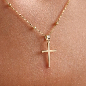 May include: A gold chain necklace with a small gold cross pendant.