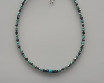 May include: A turquoise and black beaded choker necklace with a silver clasp.