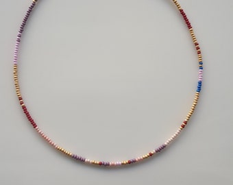 May include: A multi-colored beaded necklace with gold, pink, purple, blue, and red beads.