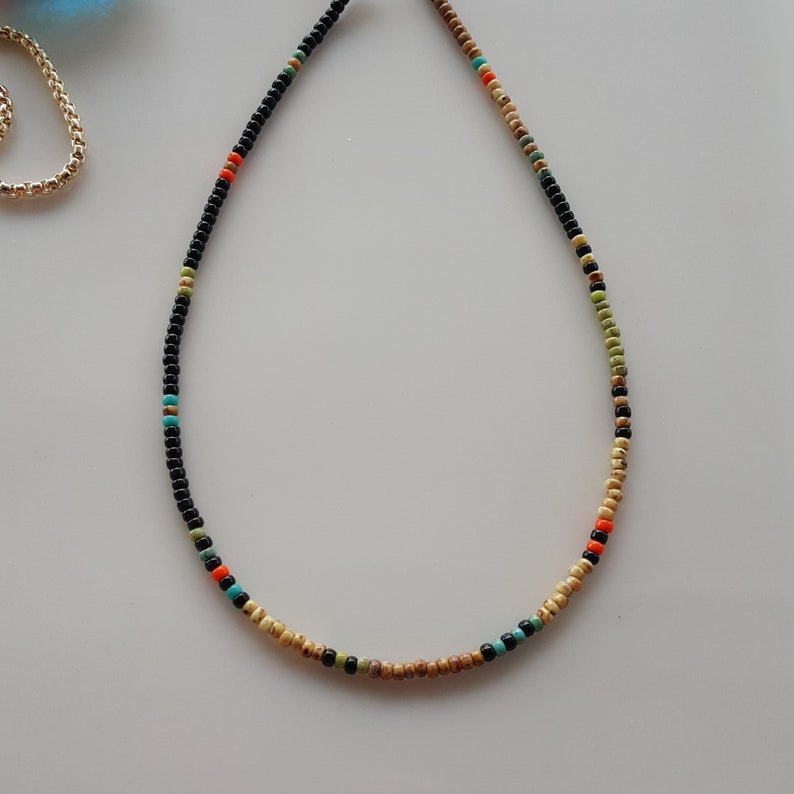 May include: A beaded necklace with black, beige, orange, green, and turquoise beads.