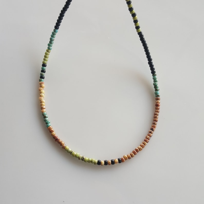 May include: A multi-coloured beaded necklace with brown, green, turquoise, and black beads.