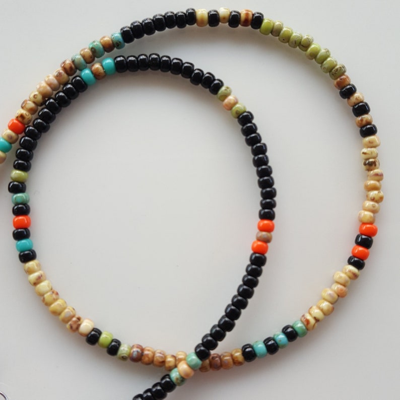 May include: A multi-colored beaded necklace with black, beige, orange, and turquoise beads.