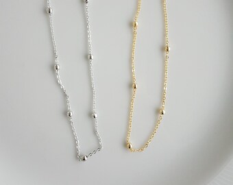 Puede incluir: Dos delicados collares con pequeñas cuentas. Un collar es plateado y el otro es dorado.