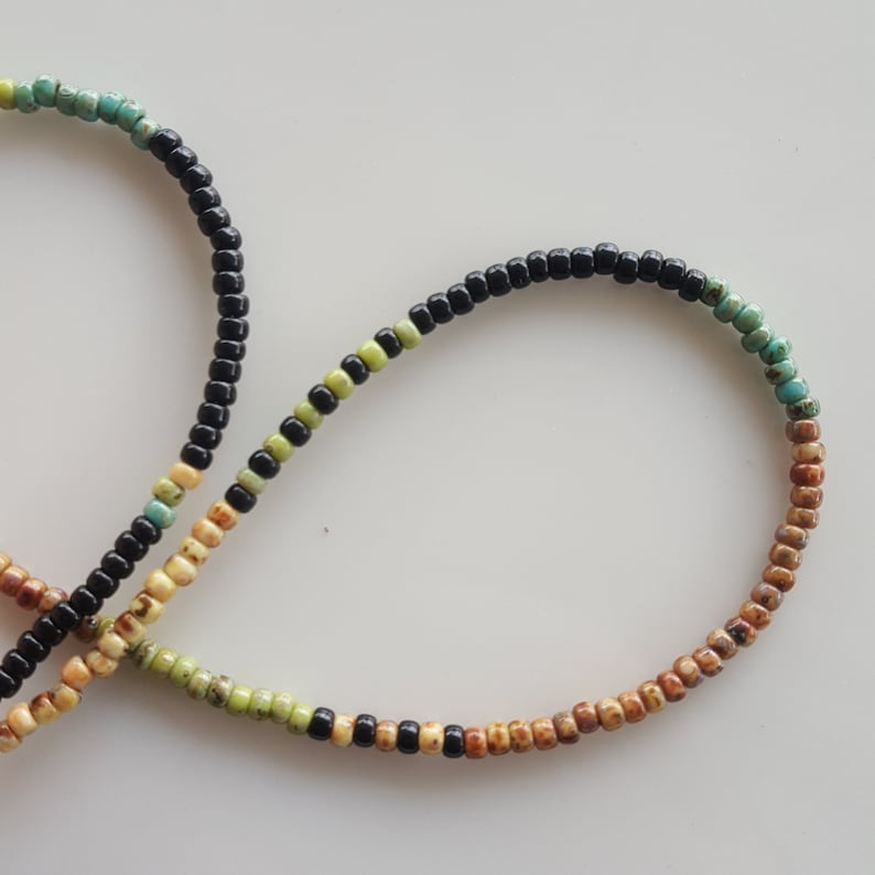 May include: A multi-coloured beaded bracelet with black, brown, yellow and green beads.