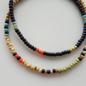 May include: Two layered necklaces with black, beige, orange, and green beads.