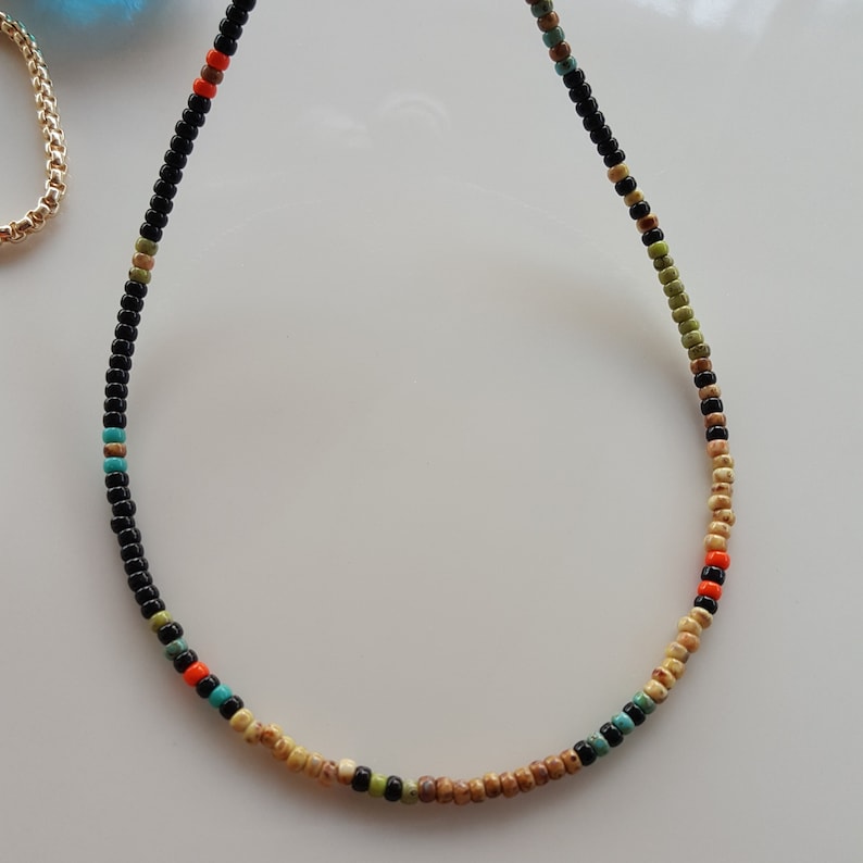 May include: A black beaded necklace with brown, orange, and turquoise beads.
