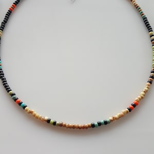May include: A beaded necklace with black, beige, orange, turquoise, and green beads.