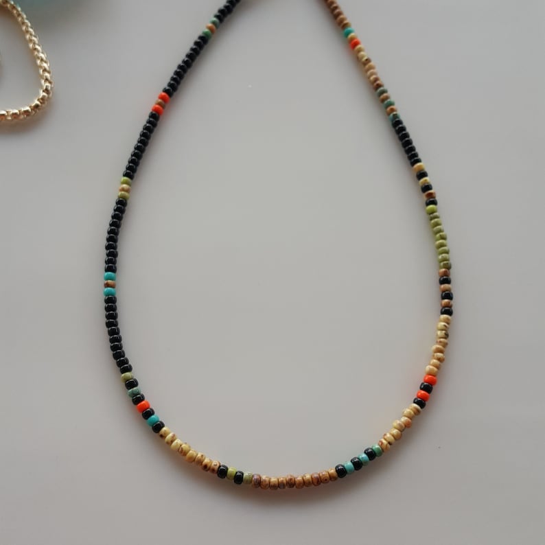 May include: A beaded necklace with black, brown, orange, and turquoise beads.