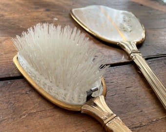 Set of antique hand mirror with matching hair brush in tones of silver and gold