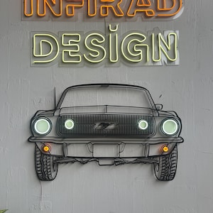 May include: A wall-mounted metal art piece depicting the front view of a classic car with illuminated circular headlights and amber turn signals. Above the car, a neon sign displays the text INFIRAD in orange and DESIGN in yellow.