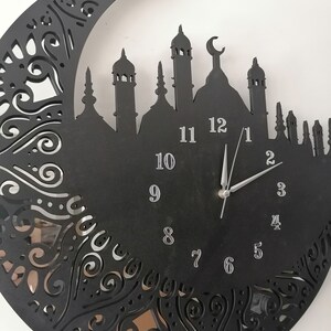 May include: Black clock with a crescent moon and mosque silhouette design. The clock face has silver numbers 1 through 12 and silver hands.