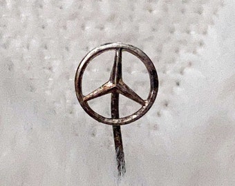 May include: A silver pin with a three-pointed star in a circle.
