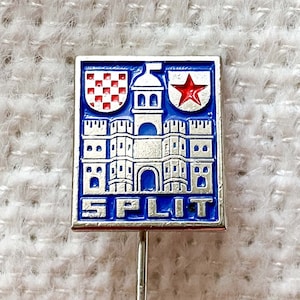 Könnte beinhalten: Eine blaue und silberne Emaille-Anstecknadel mit einem weißen Schloss und einem roten Stern. Die Nadel trägt unten die Aufschrift "SPLIT".