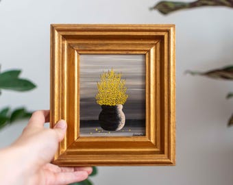 May include: A framed painting of a yellow flower arrangement in a grey pot on a grey background.