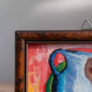 May include: A framed abstract painting with a blue, red, yellow, and green color scheme. The painting depicts a still life with a vase and other objects.