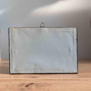 May include: A black picture frame with a white mat and a metal hanging hook on the back.