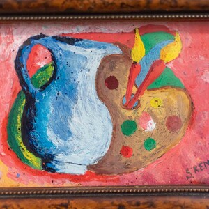 May include: A framed painting of a blue pitcher and a brown artist's palette with colorful paint on it. The background is a bright red and yellow. The painting is signed "S. Kenig 68."