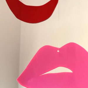 Pu&ograve; includere: Due labbra di carta appese a una corda. Il labbro superiore &egrave; rosso e il labbro inferiore &egrave; rosa.