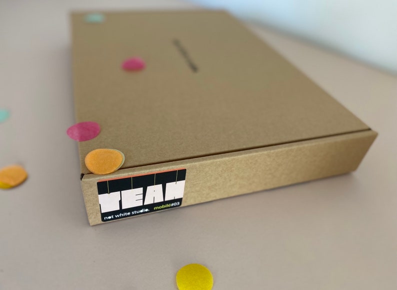 Pu&ograve; includere: Una scatola di cartone marrone con un adesivo che dice "YEAN net white studio mobile#03".