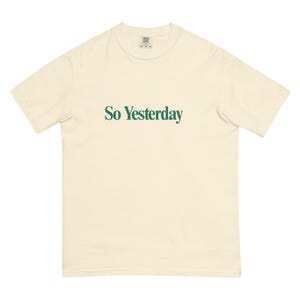 Op de afbeelding: Crèmekleurig T-shirt met de tekst "So Yesterday" in groen, gecentreerd op de voorkant. Het shirt heeft korte mouwen en een ronde hals. De stof lijkt zacht en comfortabel.